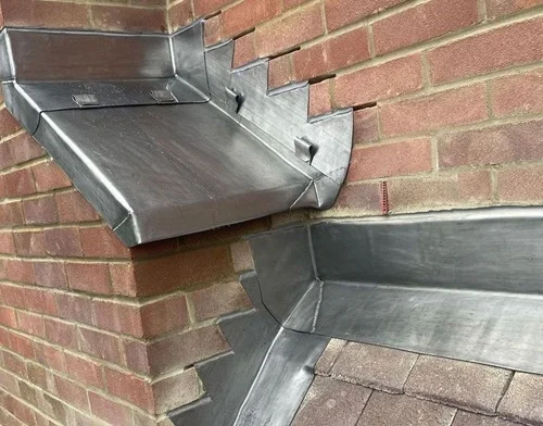 Nieuwe loodslabben, gesneden en gevormd rond een gerenoveerde schoorsteen.