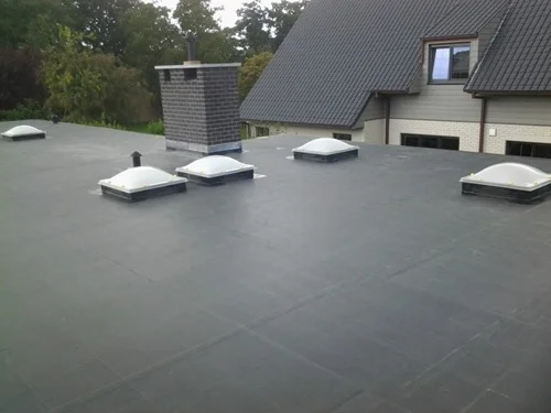 Plat EPDM-dak van een bijgebouw van een huis, met lichtkoepels.